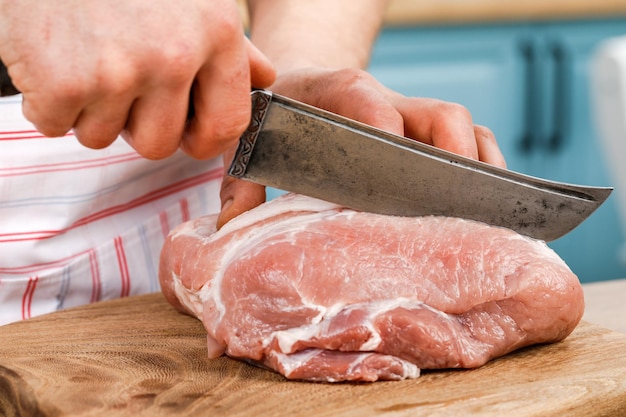 El cocinero corta un trozo de carne fresca corta la carne en la cocina