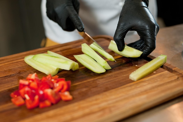 El cocinero corta las verduras con un cuchillo para preparar el plato Cortando verduras