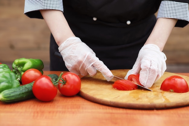 El cocinero corta verduras frescas de la granja para cenar en la mesa.