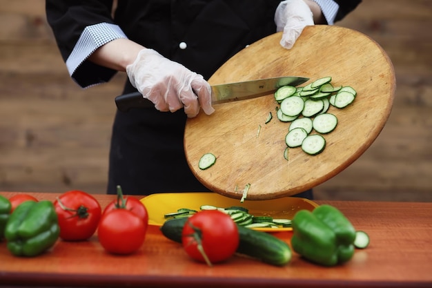 El cocinero corta verduras frescas de granja para cenar en la mesa