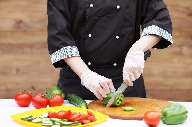 El cocinero corta verduras frescas de granja para cenar en la mesa