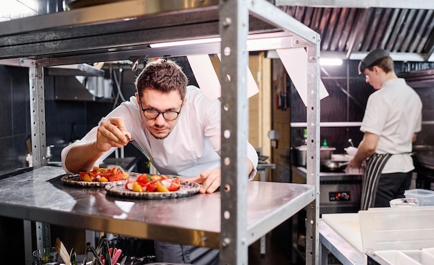 El cocinero decorando la ensalada con hierbas.