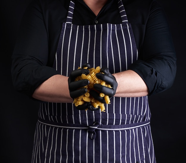 Cocinero en un delantal a rayas y guantes de látex negro sostienen fus crudo