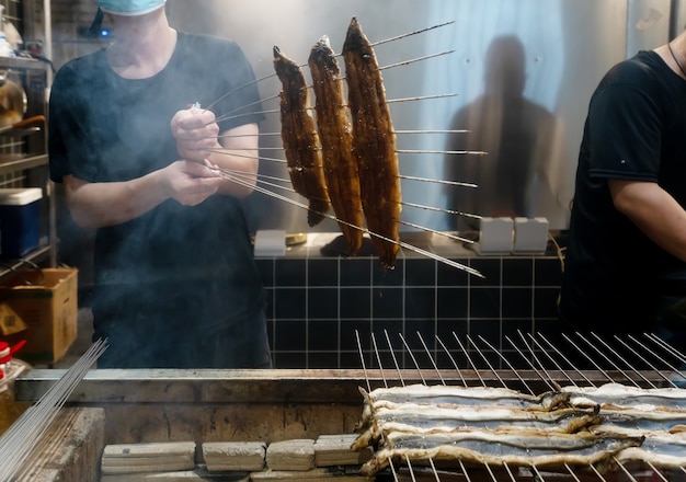 El cocinero está asando anguilas