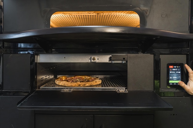 El cocinero establece un horno eléctrico para hornear la cocina del restaurante de pizza