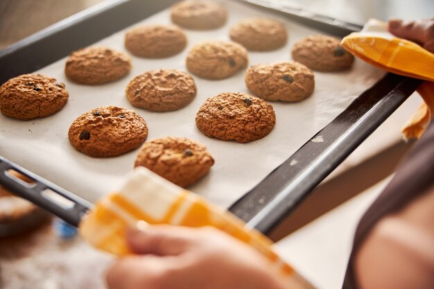 Foto cocinero experto llevando con cautela la bandeja con galletas calientes