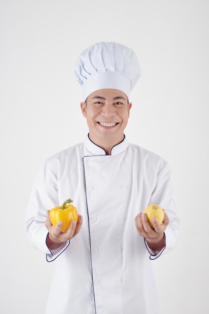 Cocinero feliz con ingredientes frescos para platos como pimiento y limón