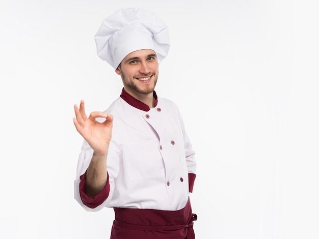 Cocinero feliz profesional positivo del hombre que muestra la muestra aceptable sabrosa aislada en el fondo blanco.