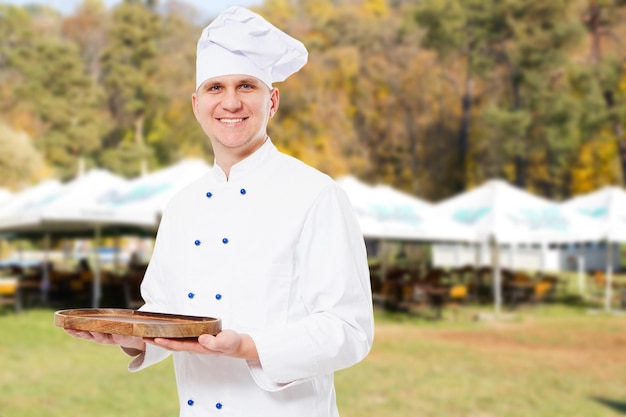Foto un cocinero feliz y sonriente preparando una muestra de comida en una bandeja de madera vacía