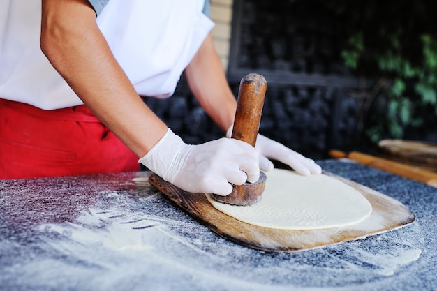 El cocinero hace una base fina para el primer plano de pizza