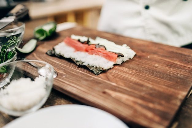 Cocinero masculino haciendo sushi en mesa de madera