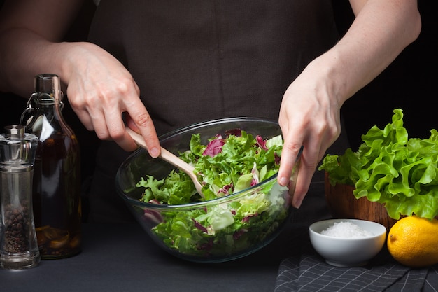 Foto cocinero de la mujer en la cocina que prepara la ensalada vegetal.