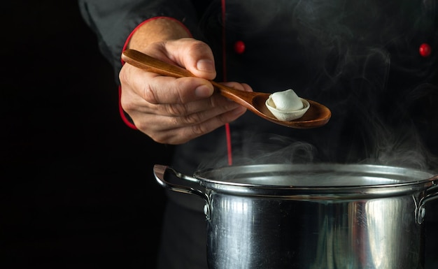 El cocinero prepara albóndigas en una sartén en la cocina Primer plano de una mano de chef sosteniendo una cuchara El concepto de cocinar un delicioso almuerzo