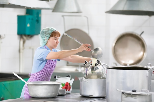 Foto el cocinero prepara la comida cocinero con sartenes grandes y un cucharón cocinero con un cucharón chef profesional