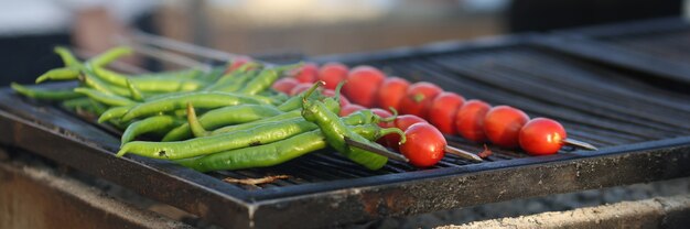 Cocinero prepara pimientos verdes y tomates asados