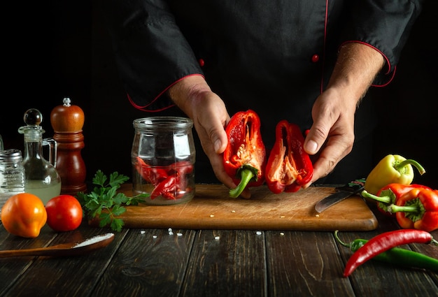 El cocinero prepara verduras frescas en la cocina El cocinero sostiene pimienta fresca cortada en sus manos Concepto de comida saludable o vegetariana