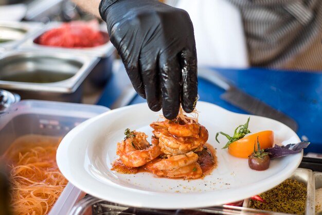 Un cocinero preparando un sabroso plato con gambas bajo la salsa.