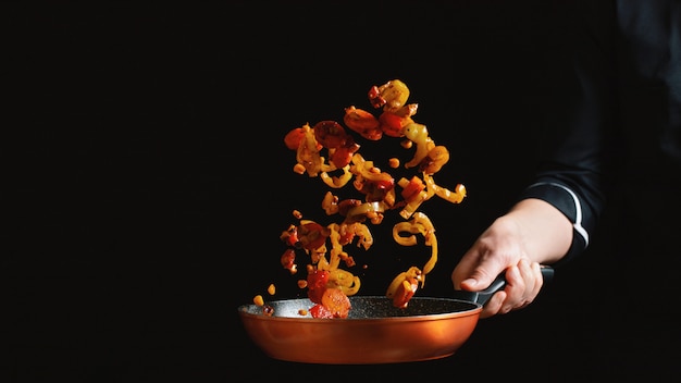 Cocinero que cocina verduras en una cacerola.