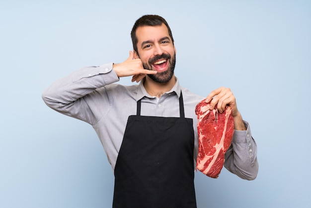 Cocinero que sostiene una carne cruda que hace gesto del teléfono. Llamame signo