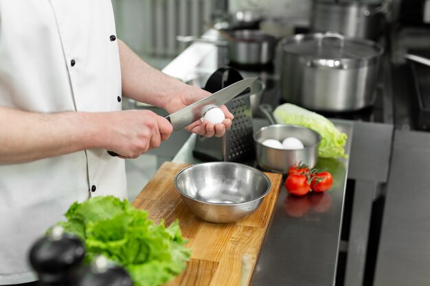 Cocinero rompe un huevo Yema de huevo cayendo en el bol