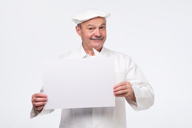 Cocinero senior hombre sujetando cartel bocadillo sonriendo encantado