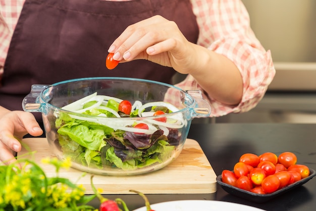 Foto cocinero de sexo femenino que hace la ensalada fresca en su hogar que cocina, diversas verduras en la tabla