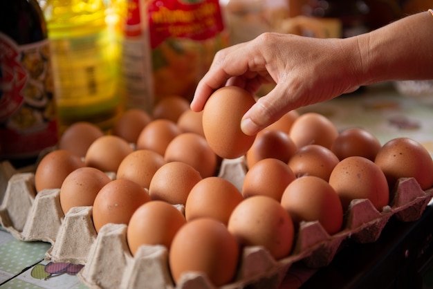 El cocinero toma los huevos de la bandeja para cocinar.