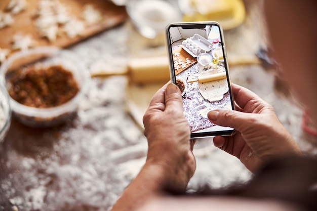 Cocinero tomando una foto del lugar de trabajo de la cocina en el teléfono inteligente