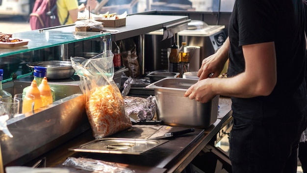 Cocinero de trabajo haciendo orden en un camión de barbacoa. Comida de la calle