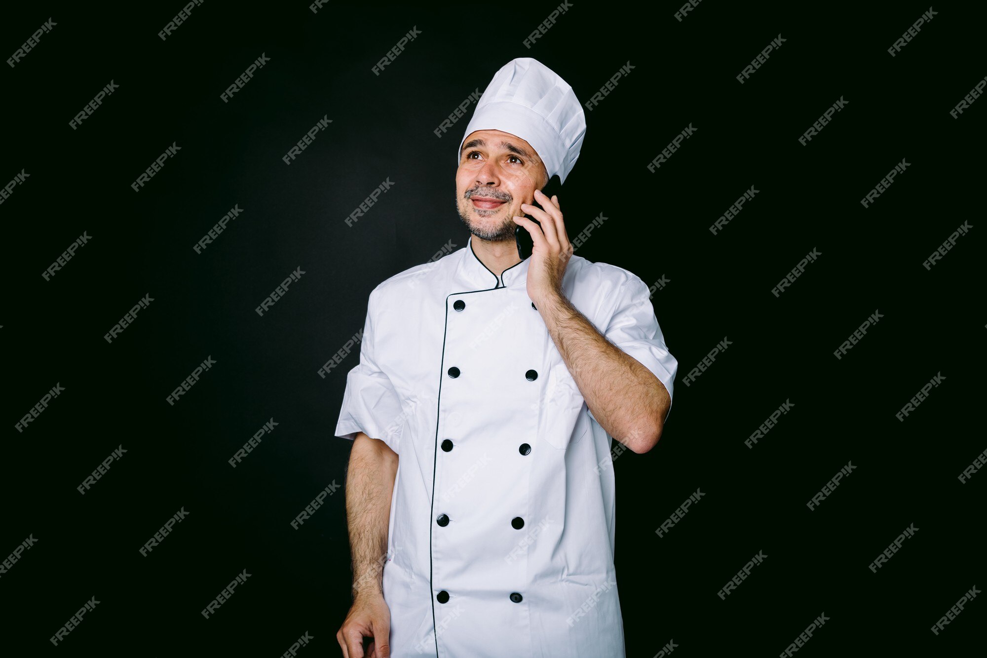 vestido con sombrero blanco y chaqueta hablando por teléfono móvil fondo negro. concepto de restaurante, comida comida para llevar. | Foto Premium