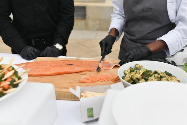 Los cocineros cortan pescado salmón en una boda.