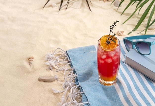 Foto cocktail amarelo vermelho tropical fresco com fatia de laranja na praia com areia branca férias no mar de verão e conceito de viagem bebidas exóticas de verão