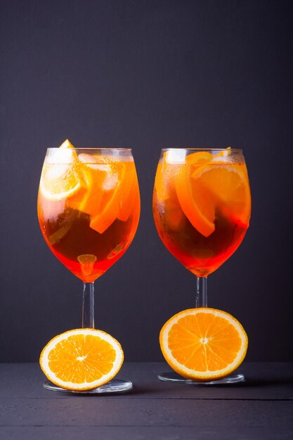 Foto cocktail aperol spritz em fundo escuro cocktail de álcool de verão com frutas de laranja e hortelã fresca