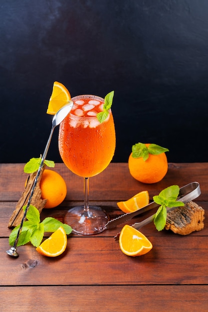 Cocktail-Aperol-Spritz und Bar-Tools. Italienischer Aperol-Spritz-Cocktail und eine in Scheiben geschnittene Orange auf dunklem Hintergrund. Aperol Spritz Cocktail mit frischer Minze