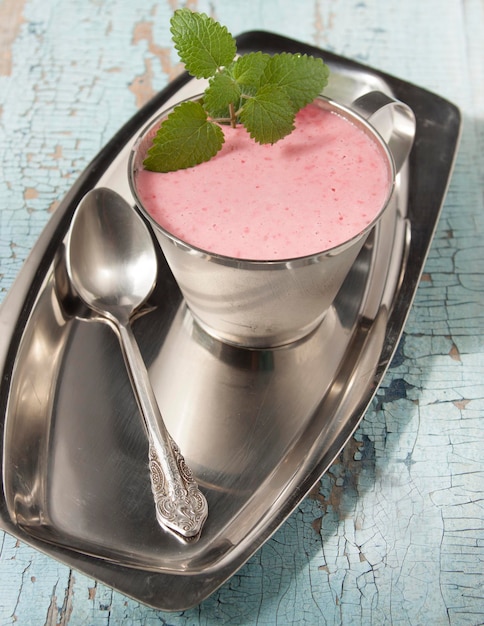 Cocktail aus gefrorenen Himbeeren mit Joghurt in einem Metallbecher auf einem Metalltablett