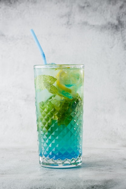 Cocktail azul com cubos de gelo e fatias de limão e limão. coctail de verão lagoa azul. limonada gelada azul. visão aérea, copie o espaço. publicidade para café. bar menu. foto vertical.