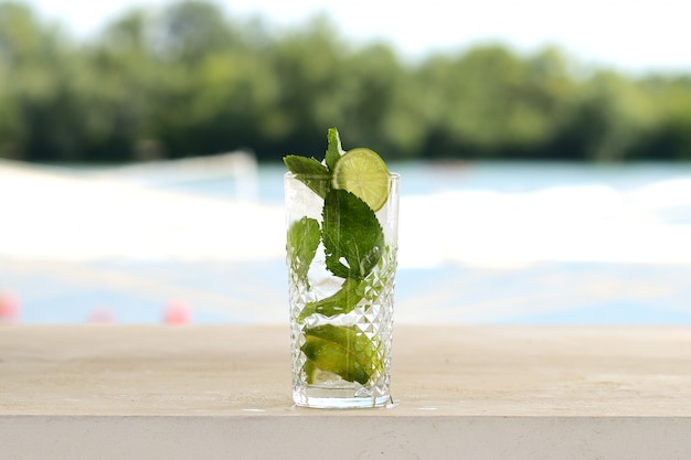 Cocktail com hortelã e gelo em um copo de vidro. Com decoração de flores e frutas