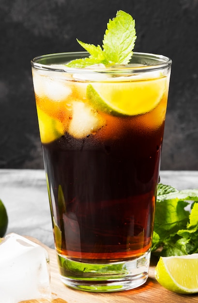 Cocktail Cuba Libre in einem Glas auf einem dunklen Hintergrund
