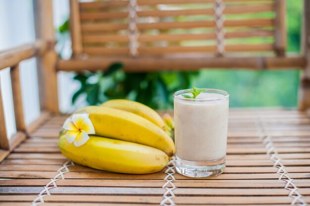 Cocktail de banana e bananas frescas em uma mesa de bambu