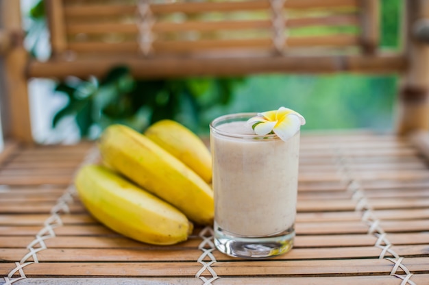 Cocktail de banana e bananas frescas em uma mesa de bambu