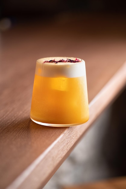 Cocktail de cor laranja com espuma branca na mesa marrom