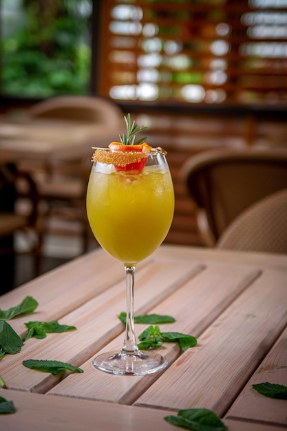 Cocktail de gin refrescante alcoólico com fatia de toranja de suco de laranja e alecrim com cubos de gelo no terraço de verão do restaurante