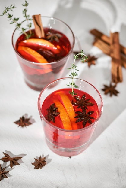 Cocktail de laranja com fatias de pera de licor de rum e tomilho em foco seletivo de mesa branca