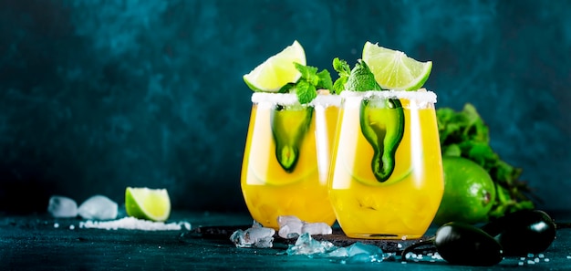 Cocktail de margarita com tequila manga suco jalapeno pimenta limão e fundo azul sal