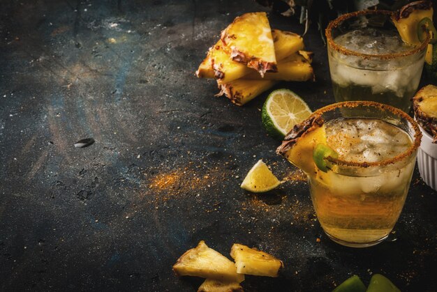 Cocktail de margarita picante de bebida mexicana com abacaxi e jalapeno e limão fundo azul escuro