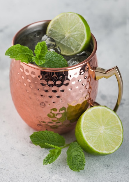 Cocktail de mula de moscou em uma caneca de cobre com limão e hortelã no fundo da mesa de cozinha leve