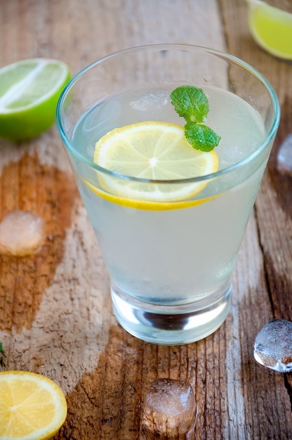 Cocktail de verão refrescante com gelo de frutas cítricas e hortelã na mesa de madeira
