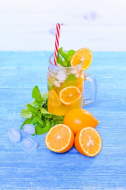 Foto cocktail do verão de mojito com hortelã, suco de lima, água de soda e gelo em uma tabela azul de madeira branca.
