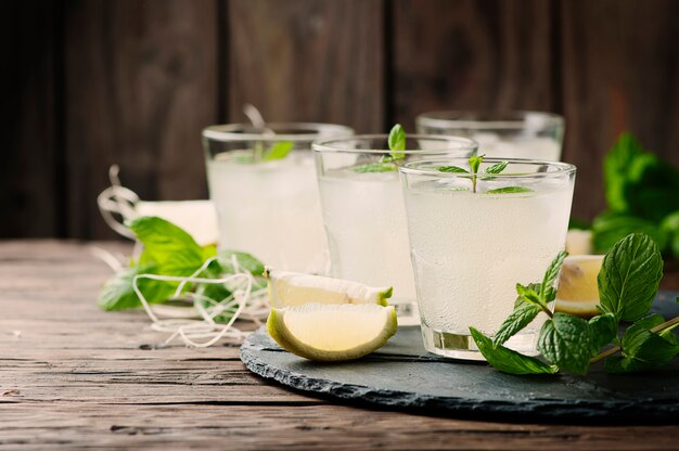 Cocktail fresco com limão, gelo e hortelã na mesa vintage