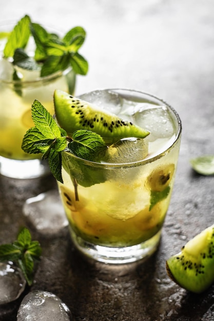 Cocktail gelado fresco com kiwi e hortelã no plano de fundo texturizado